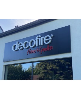 Litery blokowe 3D z logo decofire Home & Garden zamontowane na panelu reklamowym na fasadzie budynku.